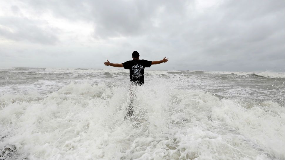 Luis Perez watches waves crash again a jetty in Galveston, Texas as Hurricane Harvey intensifies in the Gulf of Mexico Friday, Aug. 25, 2017. (AP Photo/David J. Phillip)