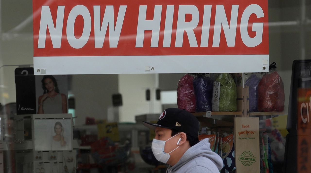 This May 7, 2020, file photo shows a man wearing a mask while walking under a Now Hiring sign at a CVS Pharmacy during the coronavirus outbreak in San Francisco. California's unemployment rate nearly tripled in April because of the economic fallout from coronavirus pandemic. (AP Photo/Jeff Chiu, File)