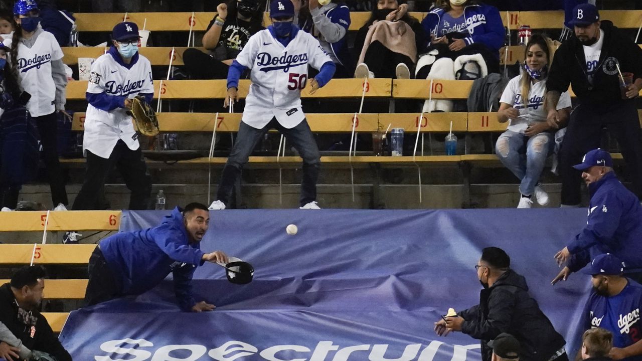 A fan reaches to try to get a home run ball hit by Los Angeles Dodgers' Will Smith during the fourth inning of a baseball game against the Cincinnati Reds Tuesday, April 27, 2021, in Los Angeles. (AP Photo/Ashley Landis)