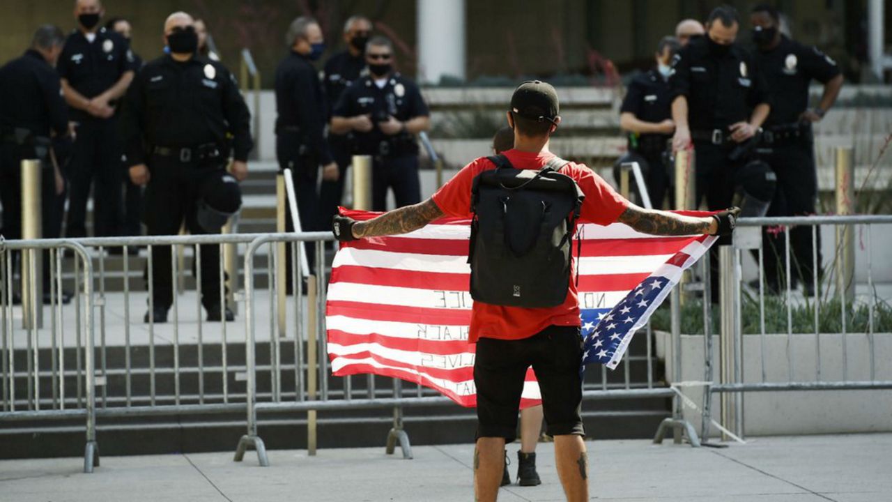 Stephen Chang of Los Angeles protests in front of police officers at Los Angeles Police Department headquarters, Thursday, June 4, 2020, in Los Angeles. Protests continue to be held in U.S. cities over the death of George Floyd, a black man who died after being restrained by Minneapolis police officers on May 25. (AP Photo/Chris Pizzello)