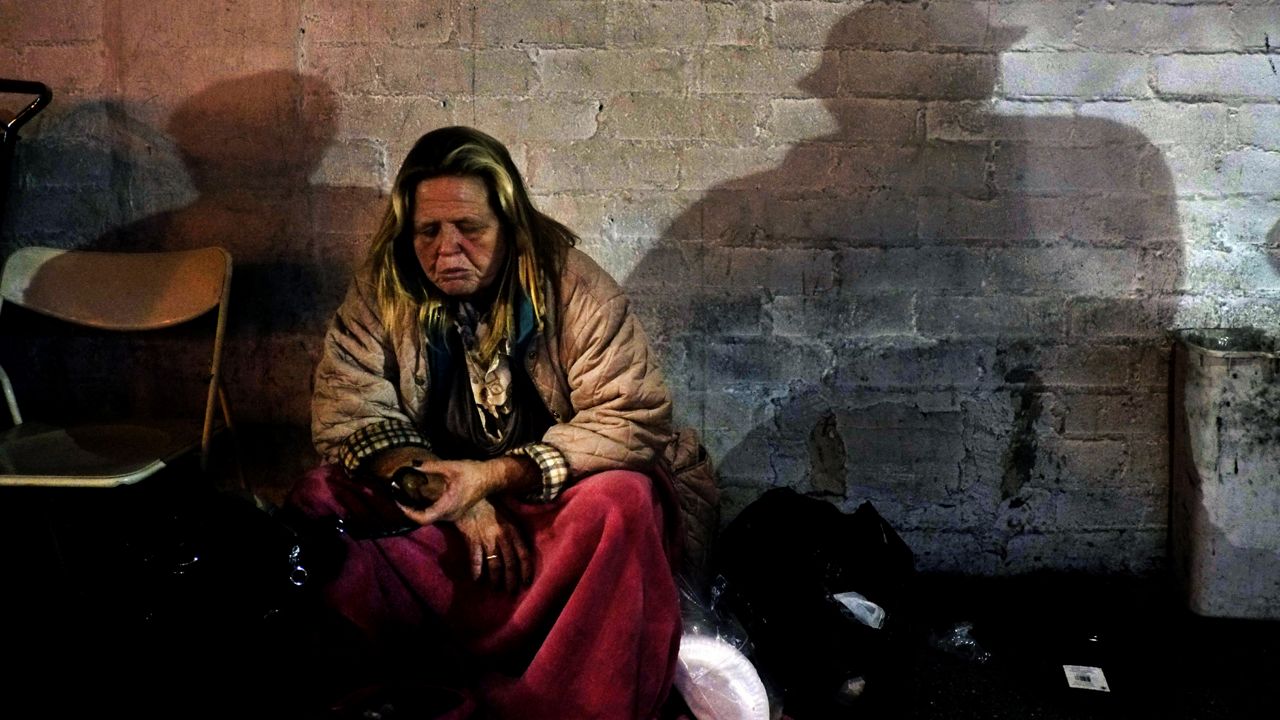 A homeless woman has a bite to eat in the Skid Row area of Los Angeles on March 21, 2013. (AP Photo/Jae C. Hong)