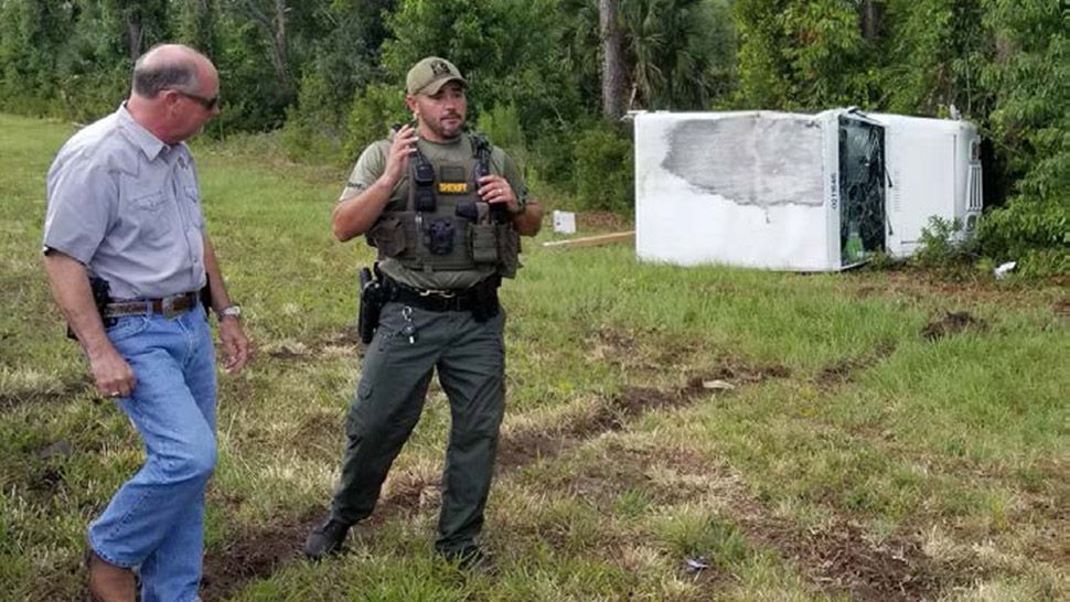 Flagler County Sheriff Rick Staly, left, and a deputy stand near a stolen mail truck that crashed after a multi-county pursuit. The driver, 29-year-old Jesse Estep was taken into custody. (Courtesy of Flagler County Sheriff's Office)