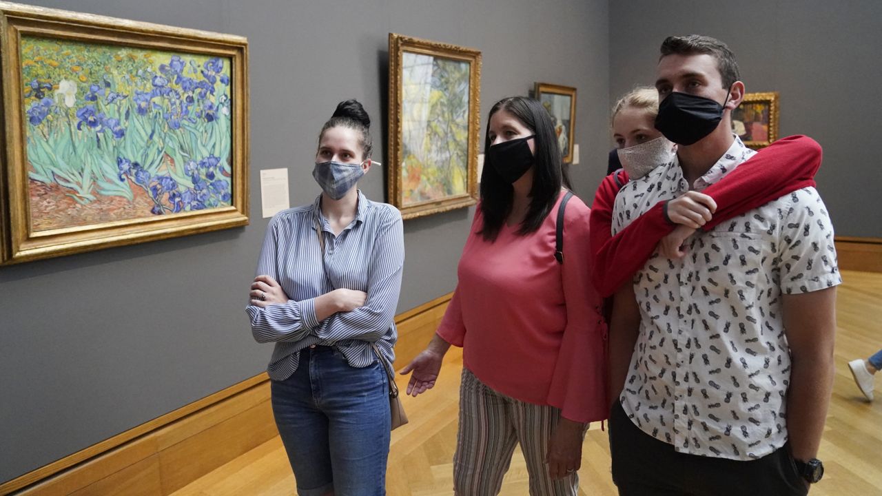 Visitors wear masks as they view art, including Vincent van Gogh's "Irises", at left, at the newly re-opened Getty Center amid the COVID-19 pandemic, Wednesday, May 26, 2021, in Los Angeles. (AP Photo/Marcio Jose Sanchez)
