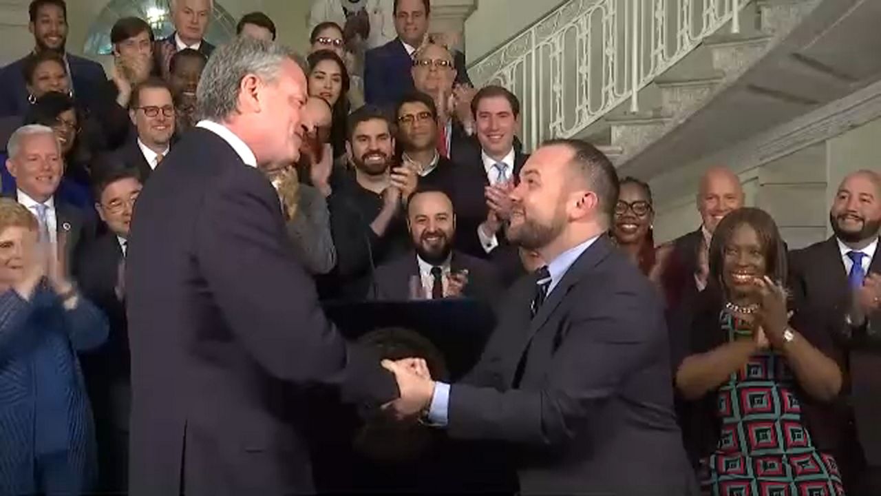 Bill de Blasio and Corey Johnson shaking hands in City Hall.