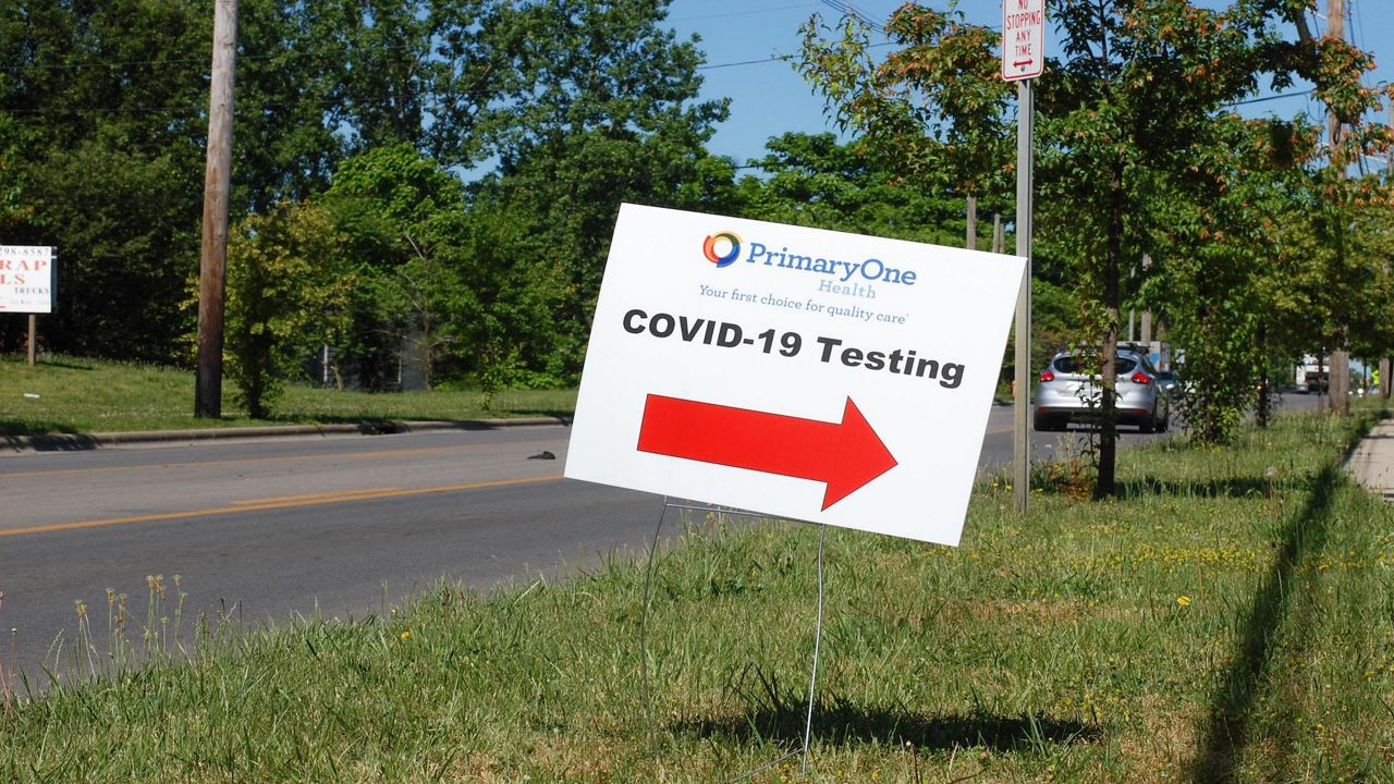 A sign that says COVID-19 Testing with a red arrow pointing to the right