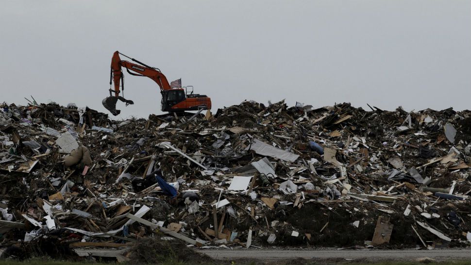 In this Friday, Sept. 29, 2017 photo, an excavator is used to move a mountain of debris created in the wake of Hurricane Harvey, Port Aransas, Texas. The storm damaged or destroyed 80 percent of local homes and businesses and arrived just before Labor Day, wiping out the lucrative summer season's final weeks. (AP Photo/Eric Gay)