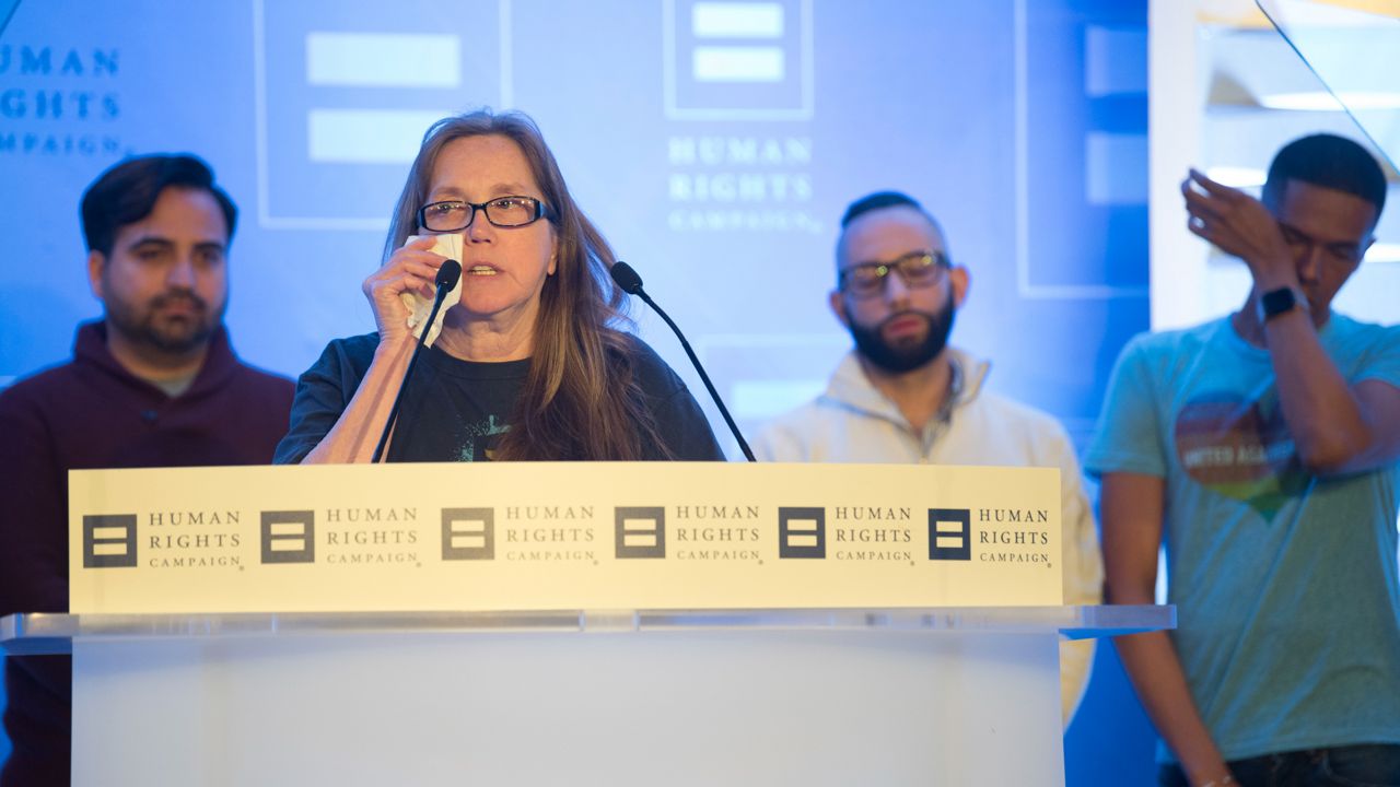 In this file photo from Saturday, March 24, 2018, Christine Leinonen, the mother of Pulse nightclub victim Christopher "Drew" Leinonen, wipes away a tear while speaking at the 2018 Human Rights Campaign's Equality Convention in Washington. Behind her are Ricardo Negron (left), Jose Arriagada (second from left) and Brandon Wolf. (Kevin Wolf/AP Images for Human Rights Campaign)