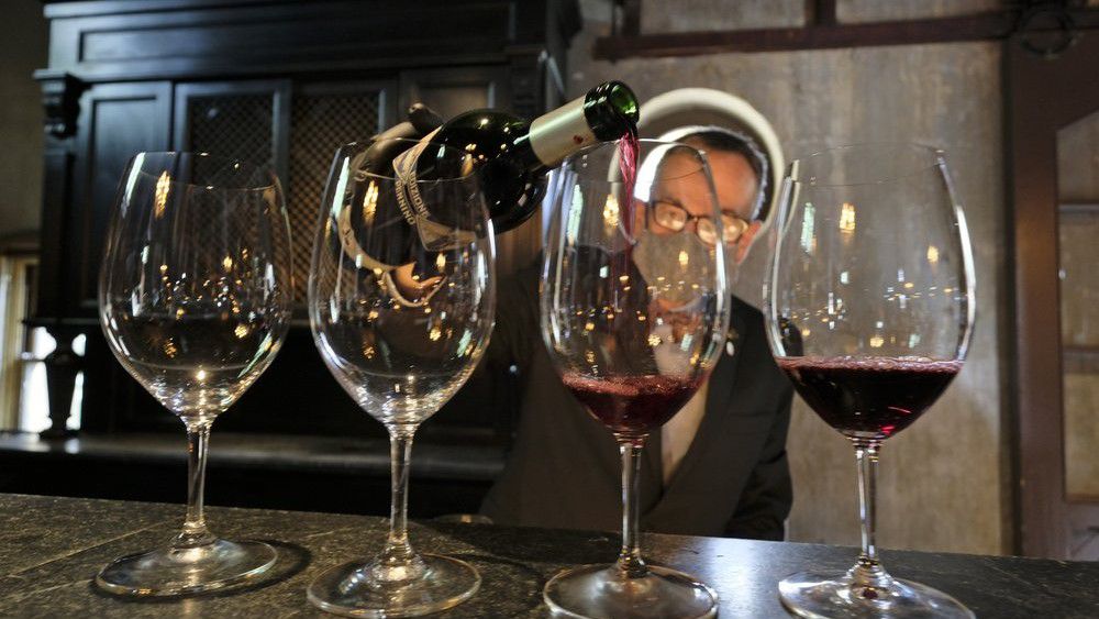 Wine educator David Mayer pours glasses of 2017 Edizione Pennino Zinfandel for guests at the Inglenook winery Friday, June 12, 2020, in Rutherford, Calif. California wineries started uncorking their bottles and welcoming people back to their tasting rooms Friday as the state's $145 billion tourism industry gears up with hotels, zoos, museums and aquariums also allowed to reopen. The historic winery, which dates to 1879, reopened Friday to wine club members after being closed since mid March because of the coronavirus threat and will be open to the public on June 25. (AP Photo/Eric Risberg)