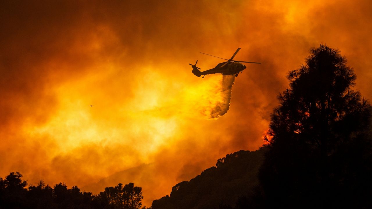 A helicopter drops water on the Lake Hughes Fire in Angeles National Forest north of Santa Clarita, Calif. on Aug. 12, 2020. (AP Photo/Ringo H.W. Chiu)