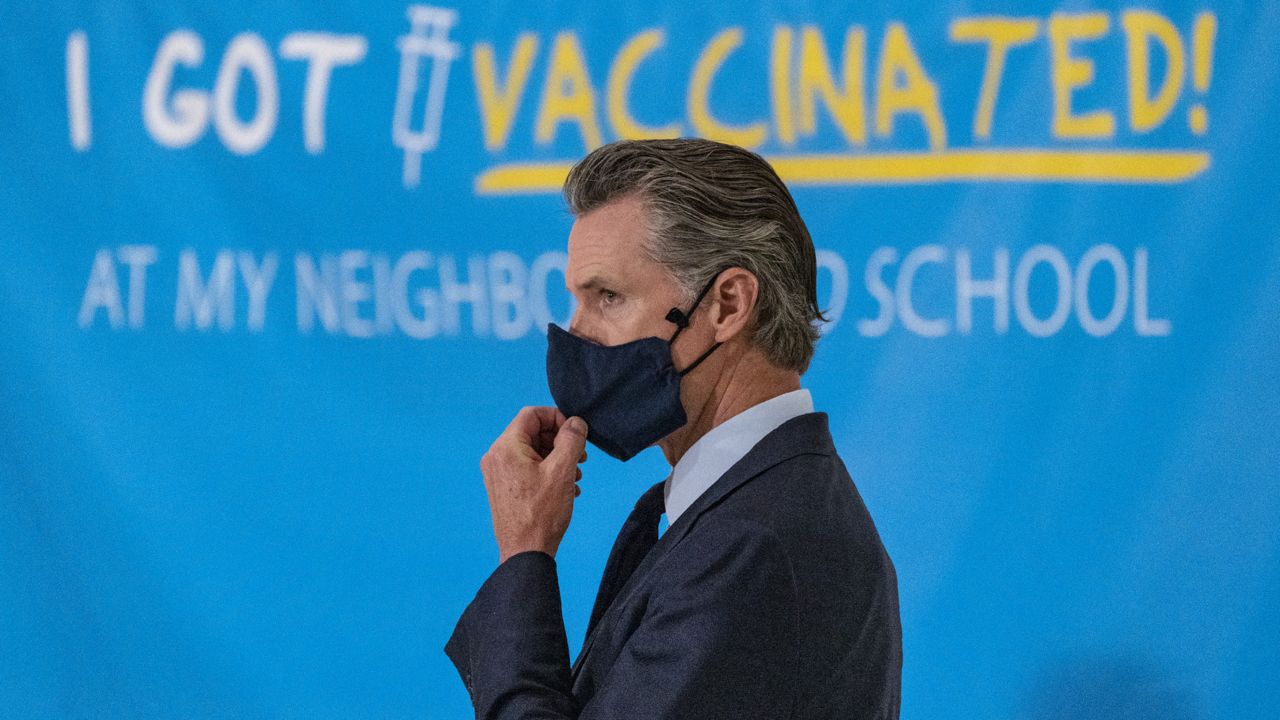 California Gov. Gavin Newsom adjusts his face mask at a news conference at the Esteban E. Torres High School in Los Angeles, May 27, 2021. (AP Photo/Damian Dovarganes)