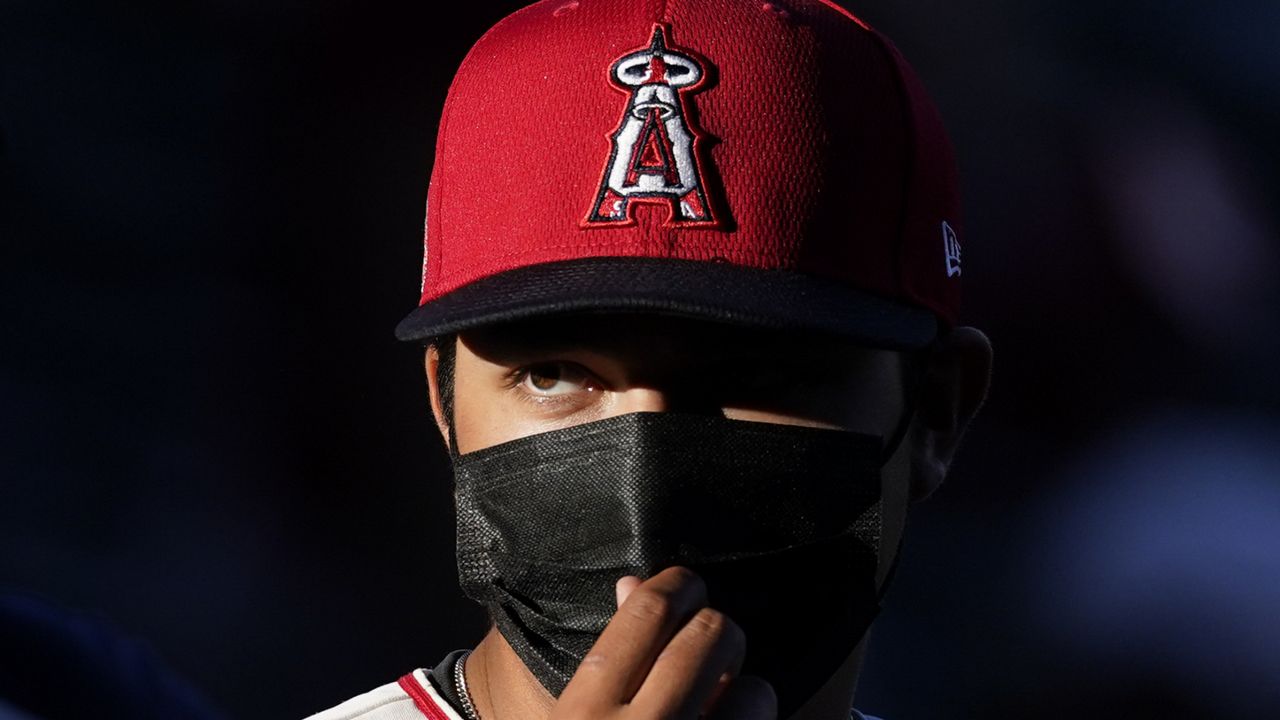 A Los Angeles Angels fan adjusts his mask before a baseball game against the Seattle Mariners Friday, June 4, 2021, in Anaheim, Calif. (AP Photo/Ashley Landis)