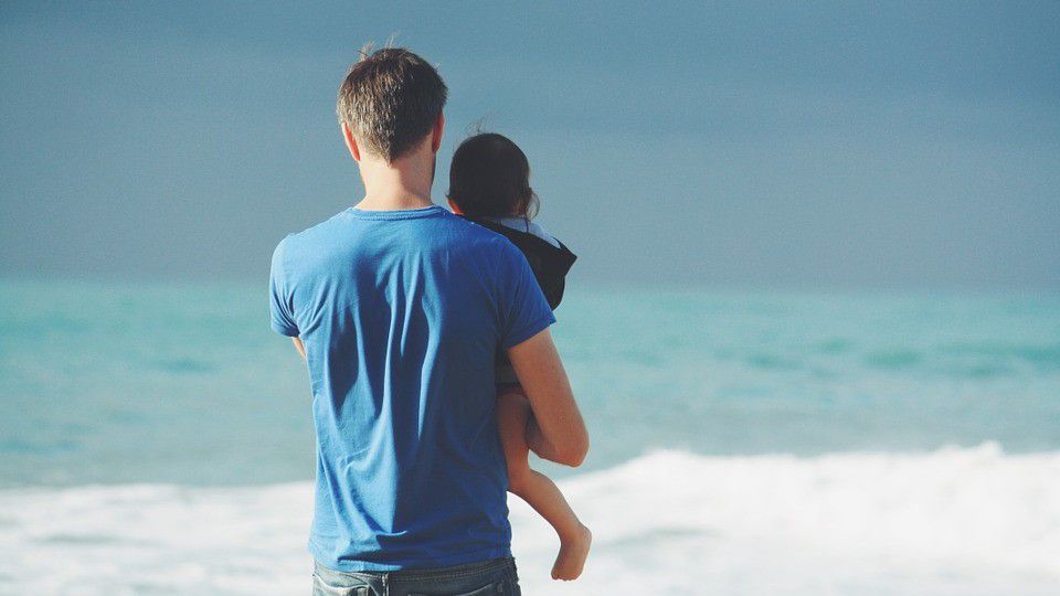 Photo of a man holding a child (Pixabay)