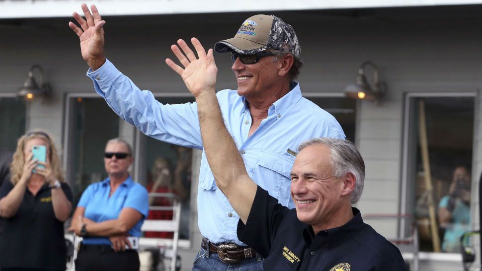 FILE - In this Sept. 21, 2017, file photo, George Strait, left, and Texas Gov. Greg Abbott wave to the crowd in Rockport, Texas, during a visit with individuals affected by Hurricane Harvey. Strait leads a new tourism campaign for Hurricane Harvey-damaged Rockport and Fulton nearly 10 months after the storm devastated the area he sometimes calls home. Officials with the Rockport-Fulton Chamber of Commerce say Strait, who's owned a house in the community for years, participated free of charge. Strait is part of the "Find Yourself in Rockport-Fulton" radio and TV campaign to encourage tourists to return to the area hard-hit when Harvey made landfall in August. (Rachel Denny Clow/Corpus Christi Caller-Times via AP, File)