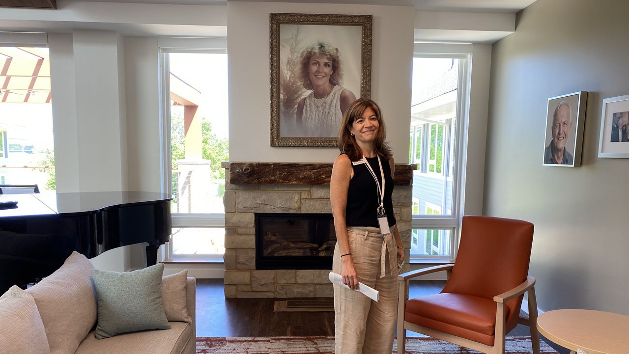 Kathy's House CEO Patty Metropulos stands in front of a portrait of Kathy Vogel Kuettner in the new home