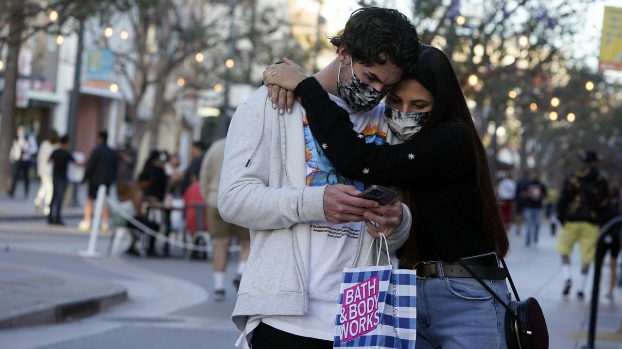 Shoppers embrace and wear masks amid the COVID-19 pandemic on The Promenade Wednesday, June 9, 2021, in Santa Monica, Calif. (AP Photo/Marcio Jose Sanchez)
