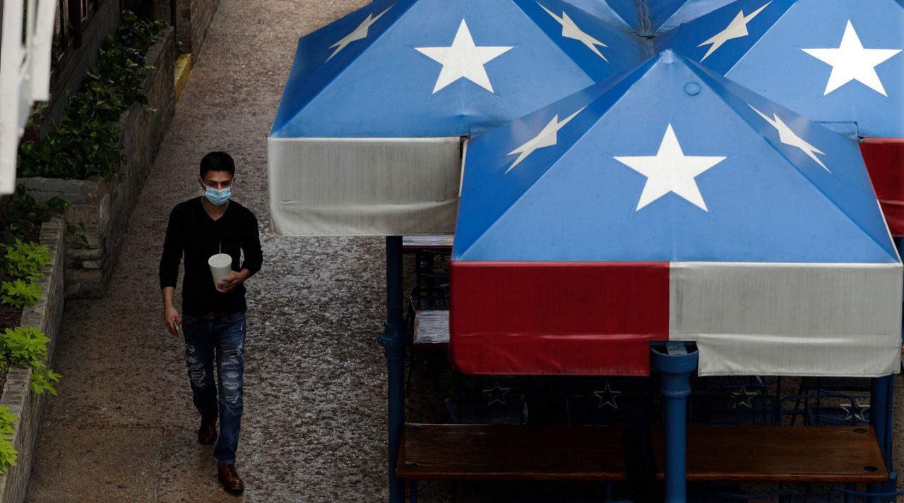 Wearing a face mask for protection as a precaution against COVID-19, a man walks along the River Walk in San Antonio, Monday, June 15, 2020, in San Antonio. Business continue to reopen after closing due to the COVID-19 pandemic. (AP Photo/Eric Gay)