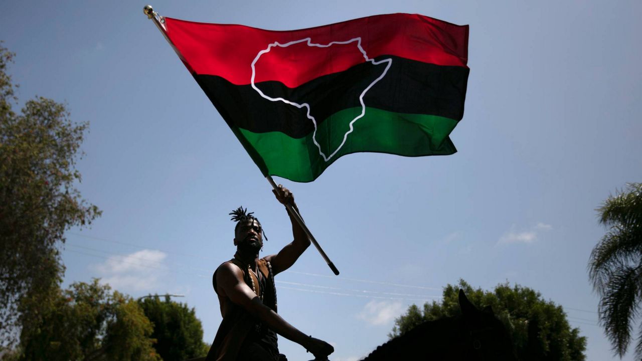 Rein Morton waves a Pan-African flag on horseback during a Juneteenth celebration in Los Angeles, June 19, 2020. (AP Photo/Jae C. Hong)