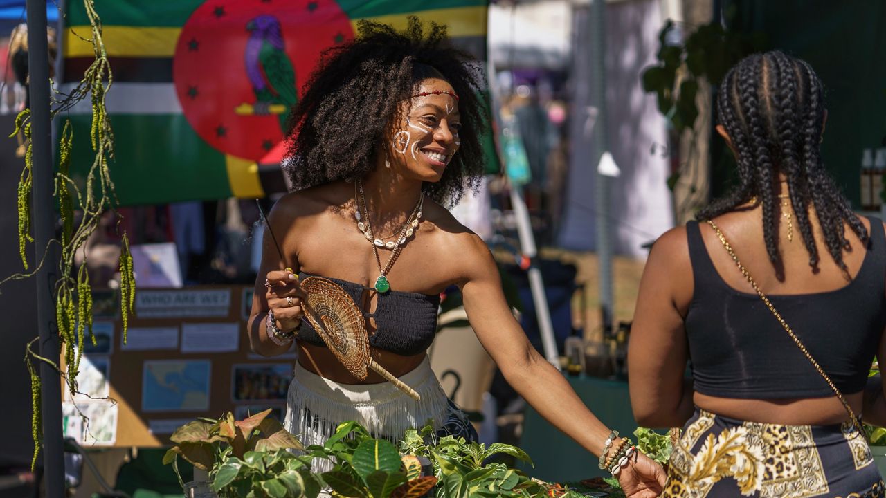 Reanna Barry, left, from Dominica, the island country in the Caribbean, sells natural products and plants during a Juneteenth commemoration at Leimert Park in Los Angeles on Saturday, June 18, 2022. (AP Photo/Damian Dovarganes)
