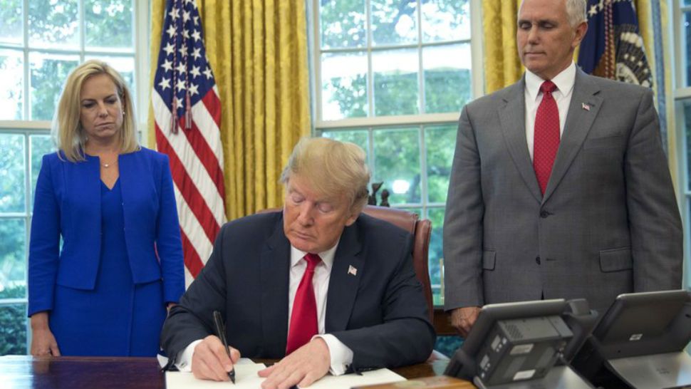President Donald Trump signs an executive order to keep families together at the border, but says that the 'zero-tolerance' prosecution policy will continue, during an event in the Oval office of the White House in Washington, Wednesday, June 20, 2018. Standing behind Trump are Homeland Security Kirstjen Nielsen, Left and Vice President Mike Pence. (AP Photo/Pablo Martinez Monsivais)