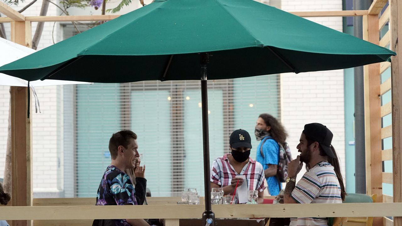 A server tends to customers in an outdoor dining area amid the COVID-19 pandemic on The Promenade Wednesday, June 9, 2021, in Santa Monica, Calif. (AP Photo/Marcio Jose Sanchez)