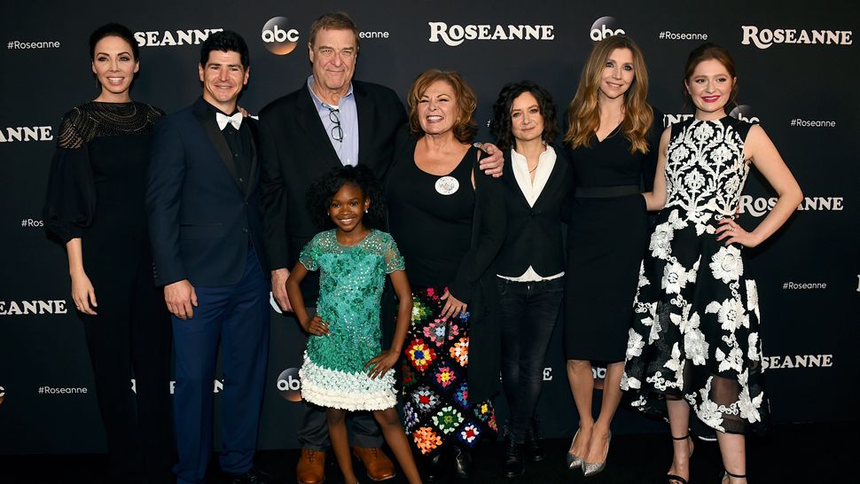 FILE - In this March 23, 2018 file photo, from left, Whitney Cummings, Michael Fishman, John Goodman, Jayden Rey, Roseanne Barr, Sara Gilbert, Sarah Chalke and Emma Kenney arrive at the Los Angeles premiere of "Roseanne" in Burbank, Calif.  ABC has canceled its hit reboot of "Roseanne", Tuesday, May 29,  following Roseanne Barr's racist tweet about former Obama adviser Valerie Jarrett. ABC Entertainment President Channing Dungey says the comment "is abhorrent, repugnant and inconsistent with our values, and we have decided to cancel the show."  (Photo by Jordan Strauss/Invision/AP, File)