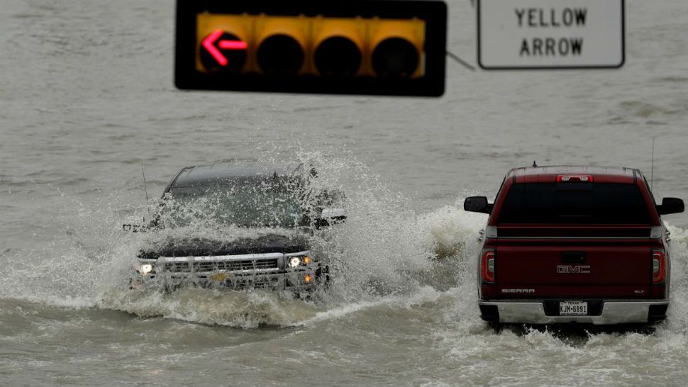 A truck is hit by the wake of another as they navigate a road that flooded after the area received several inches of rain, Wednesday, June 20, 2018, in Weslaco, Texas. (AP Photo/Eric Gay)