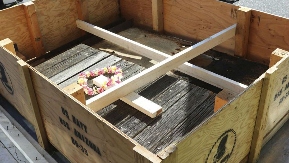 A flower lei sits on part of a wood deck and steel plate from the USS Arizona that are being held in place by white beams while sitting in a crate while waiting to be loaded onto a airplane Thursday, June 21, 2018, in Honolulu. An 800-pound chunk from the USS Arizona battleship that sank during the Japanese bombing of Pearl Harbor is heading to Texas for display at a war memorial. (AP Photo/Audrey McAvoy)