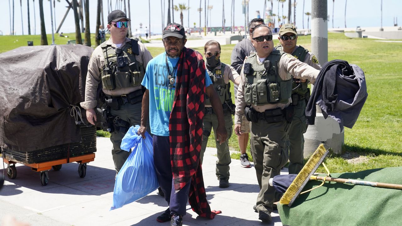 Members of the Los Angeles County Sheriffs Department's HOST, Homeless Outreach Service Team, walk with a homeless man Tuesday, June 8, 2021, in the Venice Beach section of Los Angeles. (AP Photo/Marcio Jose Sanchez)