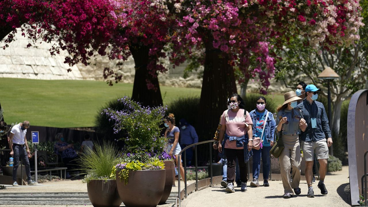 Visitors wear mask while walking the garden at the newly re-opened Getty Center amid the COVID-19 pandemic, Wednesday, May 26, 2021, in Los Angeles. (AP Photo/Marcio Jose Sanchez)