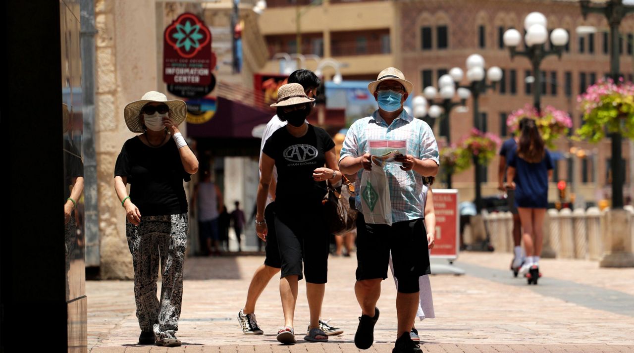 Visitors wearing masks to protect against the spread of COVID-19 walk through downtown San Antonio, Wednesday, June 24, 2020, in San Antonio. Cases of COVID-19 have spiked in Texas and the governor of Texas is encouraging people to wear masks in public and stay home if possible. (AP Photo/Eric Gay)