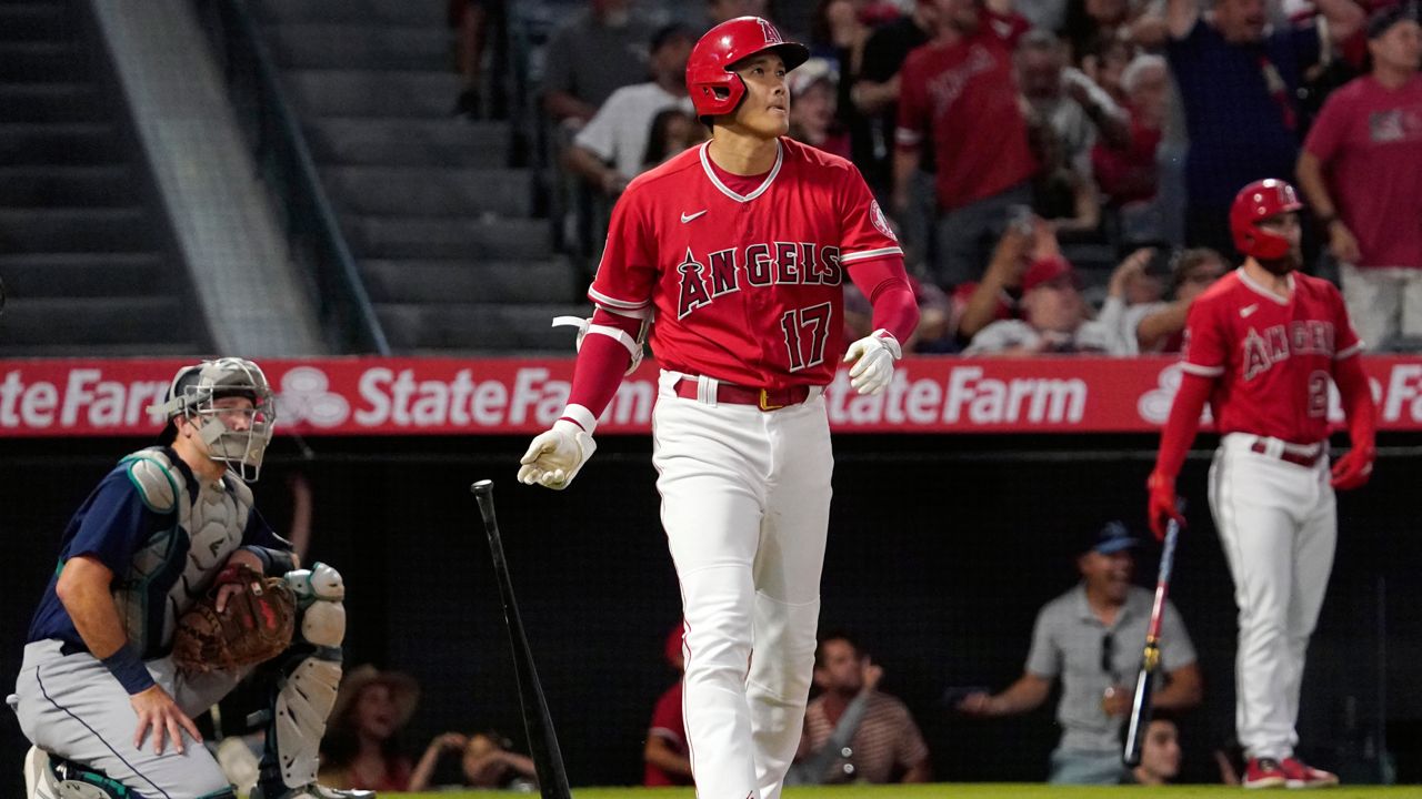 Los Angeles Angels' Shohei Ohtani, center, drops his bat as he hits a solo home run as Seattle Mariners catcher Cal Raleigh, left, watches during the third inning of a baseball game Saturday, June 25, 2022, in Anaheim, Calif. (AP Photo/Mark J. Terrill)