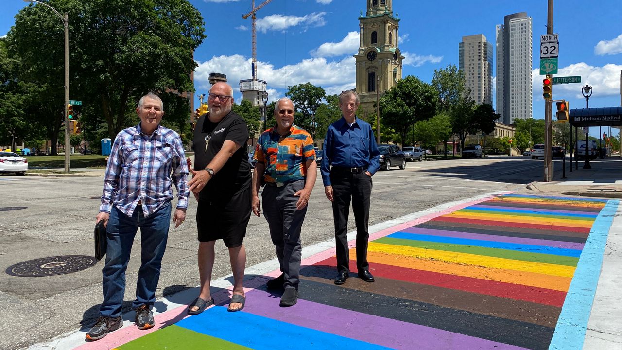 Four former GPU members walk across a rainbow-painted crosswalk in Milwaukee