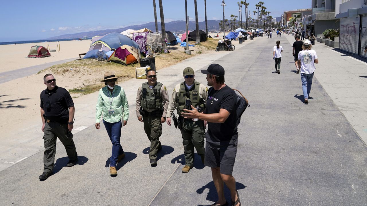Members of the Los Angeles County Sheriffs Department's Homeless Outreach Service Team, or HOST, walk past tents set up by homeless people in the Venice Beach section of Los Angeles on June 8, 2021. (AP Photo/Marcio Jose Sanchez)