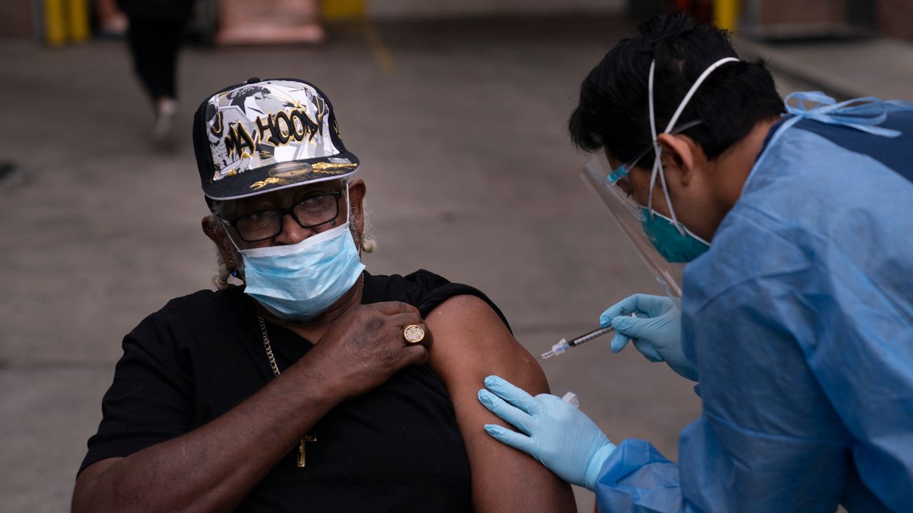 Registered nurse Angelo Bautista, right, administers a COVID-19 vaccine in the Skid Row area of Los Angeles, Wednesday, Feb. 10, 2021. (AP Photo/Jae C. Hong)