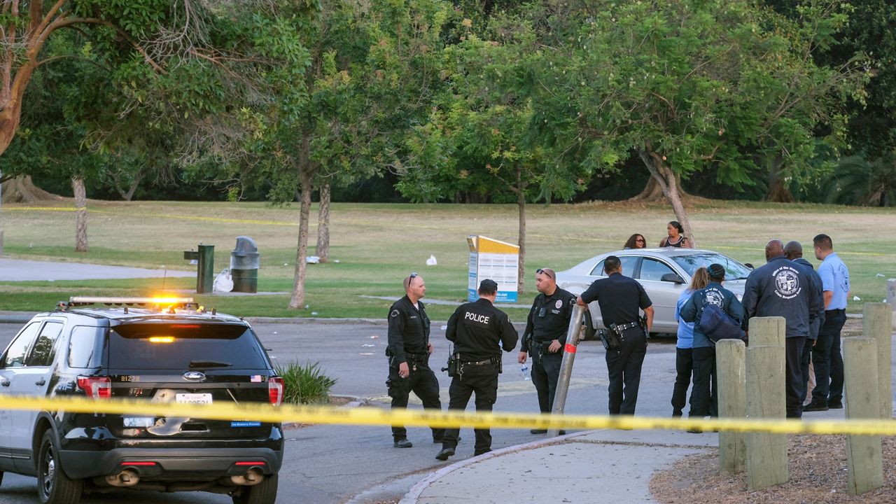 Police officers stand near the scene of a shooting at Peck Park in San Pedro, Calif., Sunday. (AP Photo/Ringo H.W. Chiu)