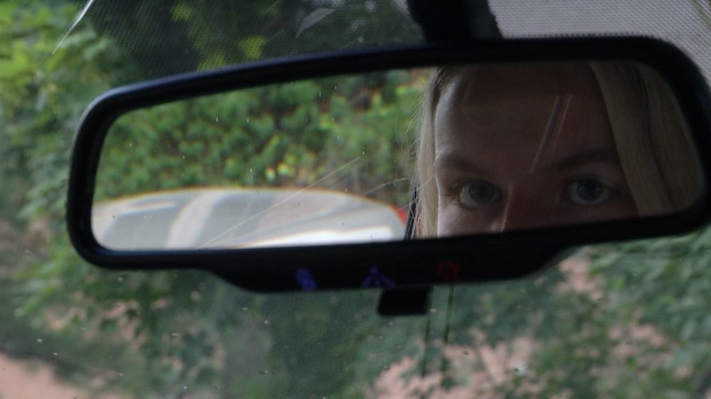 A teenager driver looks in her rearview mirror 