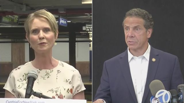 From left to right: Cynthia Nixon, wearing a white blouse; Andrew Cuomo, wearing a navy blue blazer and a white dress shirt.