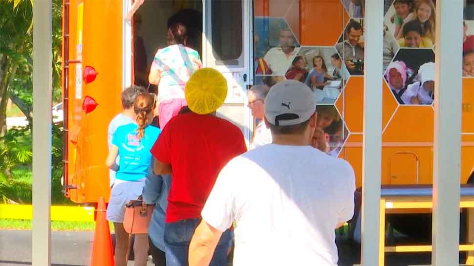 People waiting outside the Florida Department of Health of Manatee County's mobile unit awaiting Hepatitis A vaccinations during a free vaccination event at Anna Maria Elementary School in Holmes Beach, Friday, July 5, 2019. (Gabrielle Arzola/Spectrum Bay News 9)