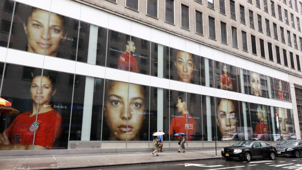 Portraits of the USA women's soccer team members are visible in the windows of a building on Fifth Avenue, in New York, Thursday, June 13, 2019. Women's soccer engages the U.S. every four years, then disappears for most fans like Brigadoon. In the wake of the Americans' record-setting fourth World Cup title Sunday, July 7, 2019, the hard part remains ahead: the weekly work of boosting the National Women's Soccer League. (AP Photo/Richard Drew)