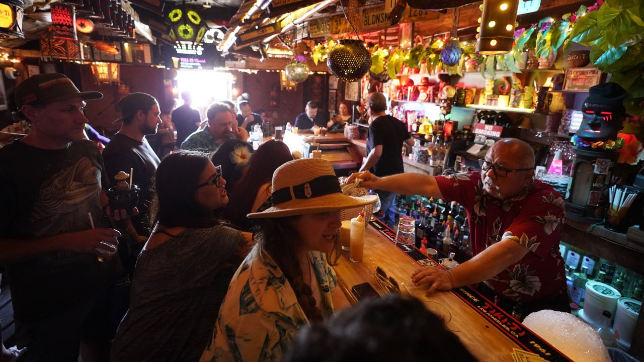 Patrons enjoy cold tropical cocktails in the tiny interior of the Tiki-Ti bar as it reopens on Sunset Boulevard in Los Angeles, Wednesday, July 7, 2021. (AP Photo/Damian Dovarganes)