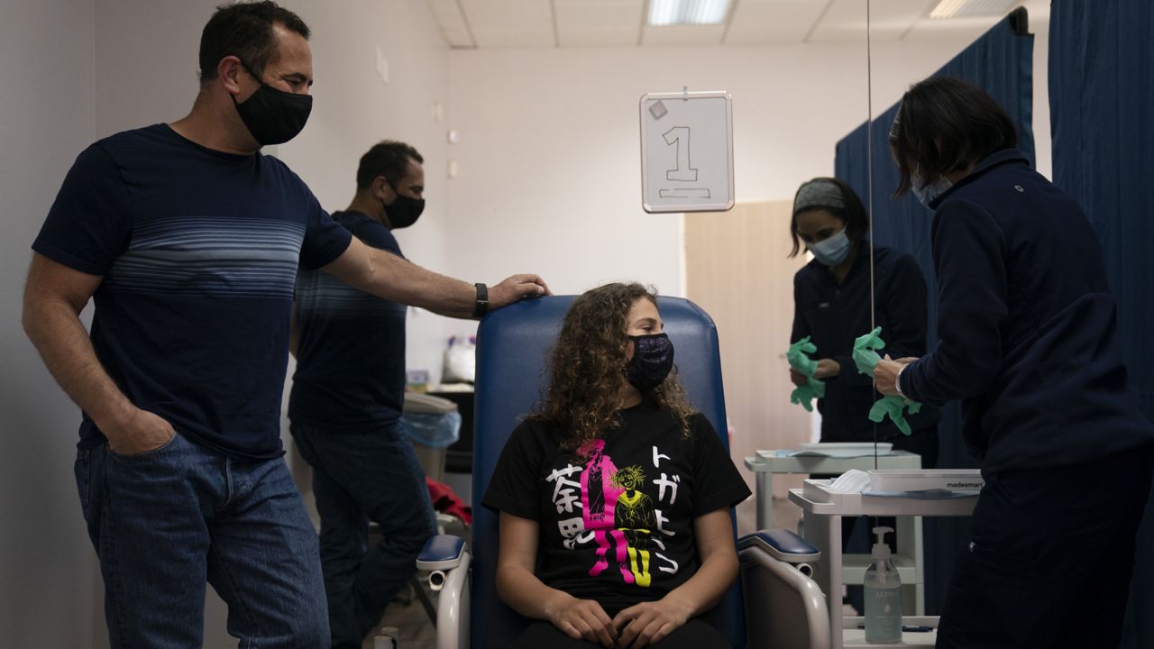 Sarah Jackman, 12, center, waits to receive the Pfizer COVID-19 vaccine from nurse practitioner Nicole Noche, right, as she is accompanied by her father, Scott, at Families Together of Orange County in Tustin, Calif., Thursday, May 13, 2021. (AP Photo/Jae C. Hong)