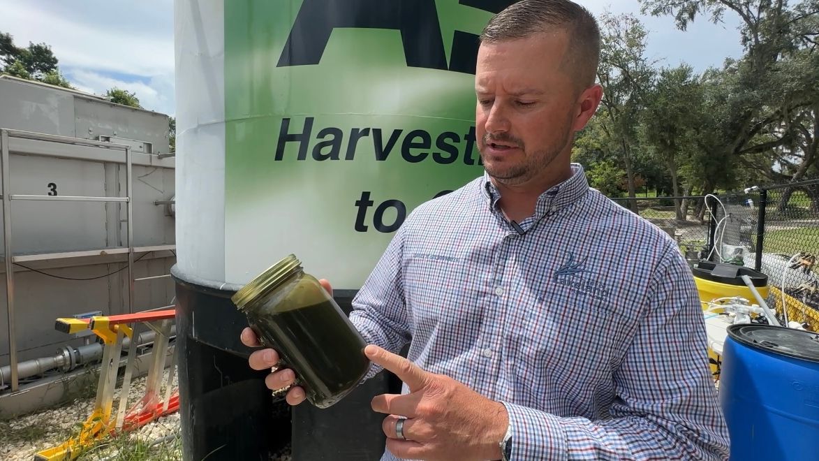 Lakes and Stormwater Supervisor Cody O’Gorman is pictured holding a jar of algae slurry. (Spectrum Bay News 9/Alexis Jones)