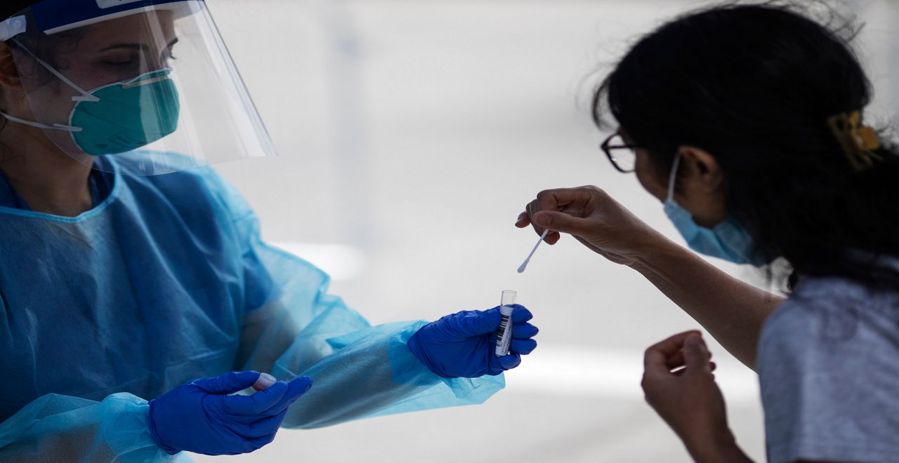 A medical professional in PPE administers a COVID-19 test (Spectrum News/File)