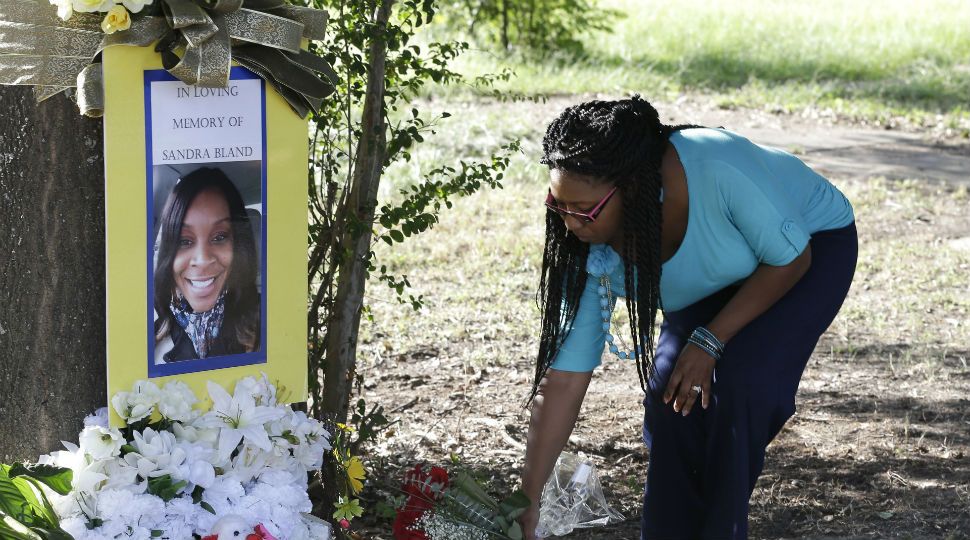 In this July 21, 2015 photo, Jeanette Williams places a bouquet of roses at a memorial for Sandra Bland near Prairie View A&M University, in Prairie View, Texas. (AP Image)