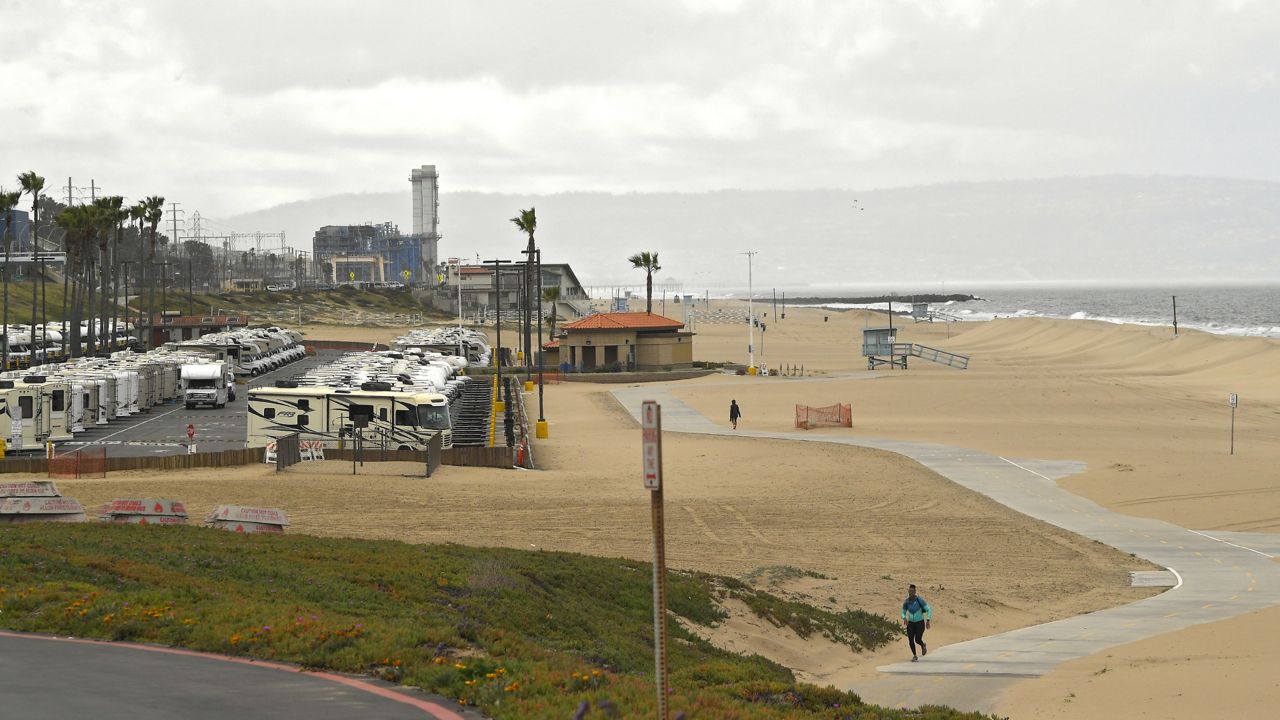 Recreational vehicles sit lined up in a parking lot along Dockweiler State Beach on Thursday, March 19, 2020, in Los Angeles. (AP Photo/Mark J. Terrill)
