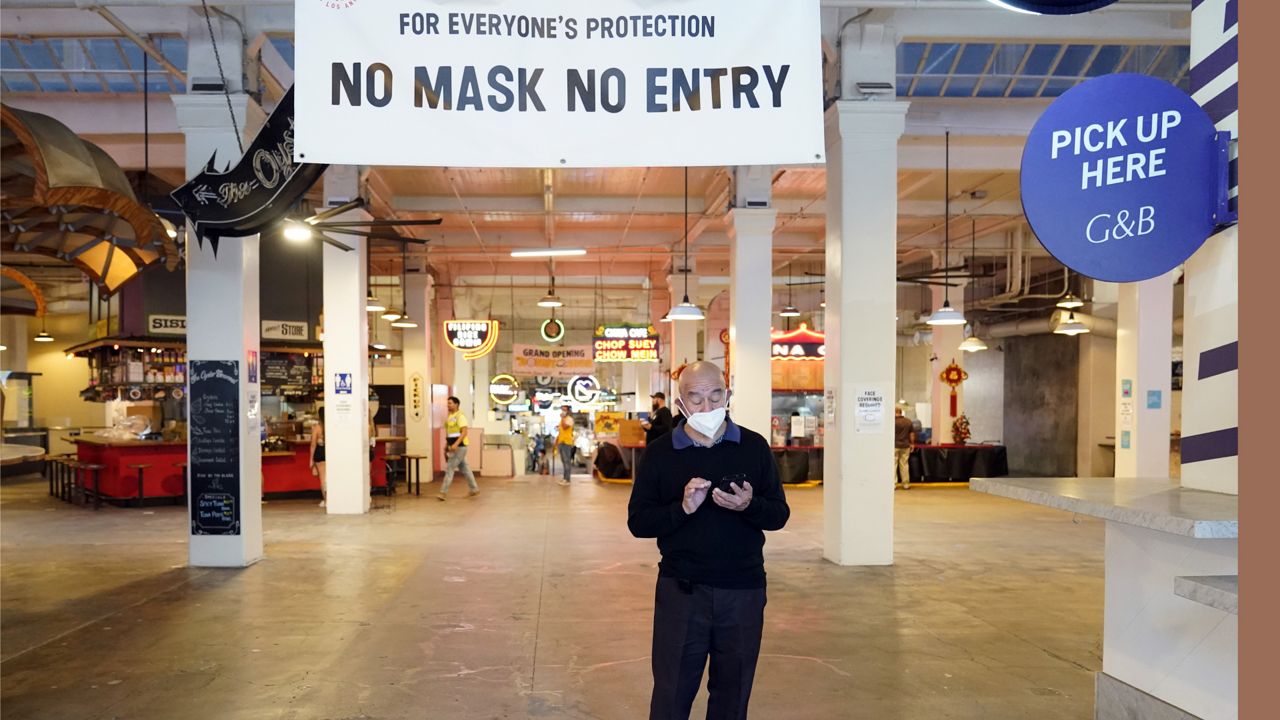 A sign points to a mask mandate at the Grand Central Market in Los Angeles on Nov. 16, 2020. (AP Photo/Marcio Jose Sanchez)