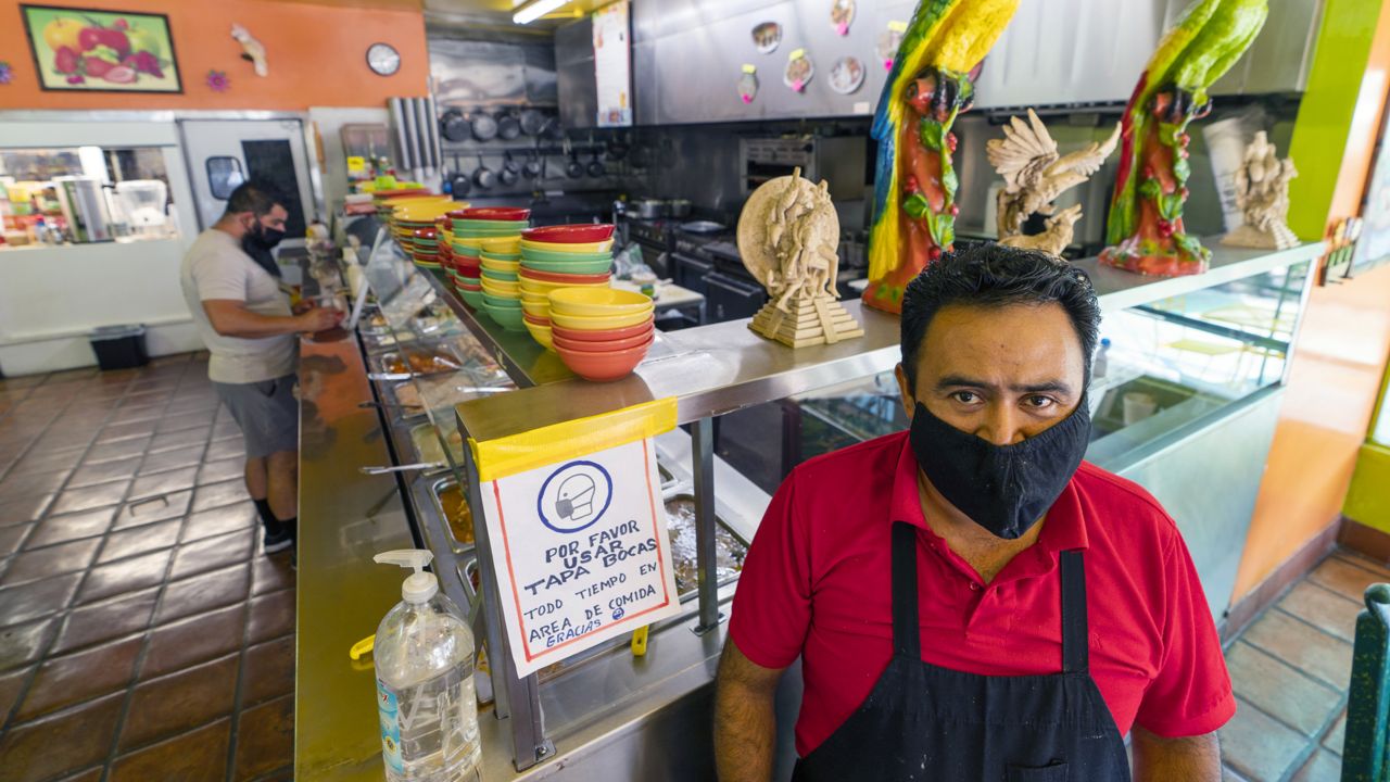 Adrian Luna, owner of the Taqueria El Sol buffet in Los Angeles' Boyle Heights neighborhood, stands in the buffet area of his restaurant in Los Angeles, Thursday, July 22, 2021. (AP Photo/Damian Dovarganes)