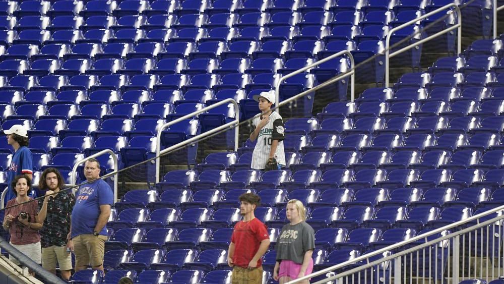 Baseball fans stand during the singing of the National Anthem before the start of a baseball game between the Miami Marlins and the Texas Rangers, Thursday, July 21, 2022, in Miami. (AP Photo/Wilfredo Lee, File)