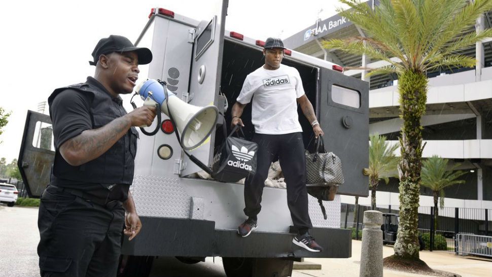Comedian Ha Ha Davis, left, announces the arrival of Jacksonville Jaguars cornerback Jalen Ramsey to NFL football training camp as he steps from the back of an armored car outside TIAA Bank Field in Jacksonville, Fla., Wednesday, July 24, 2019. (Bob Self/The Florida Times-Union via AP)