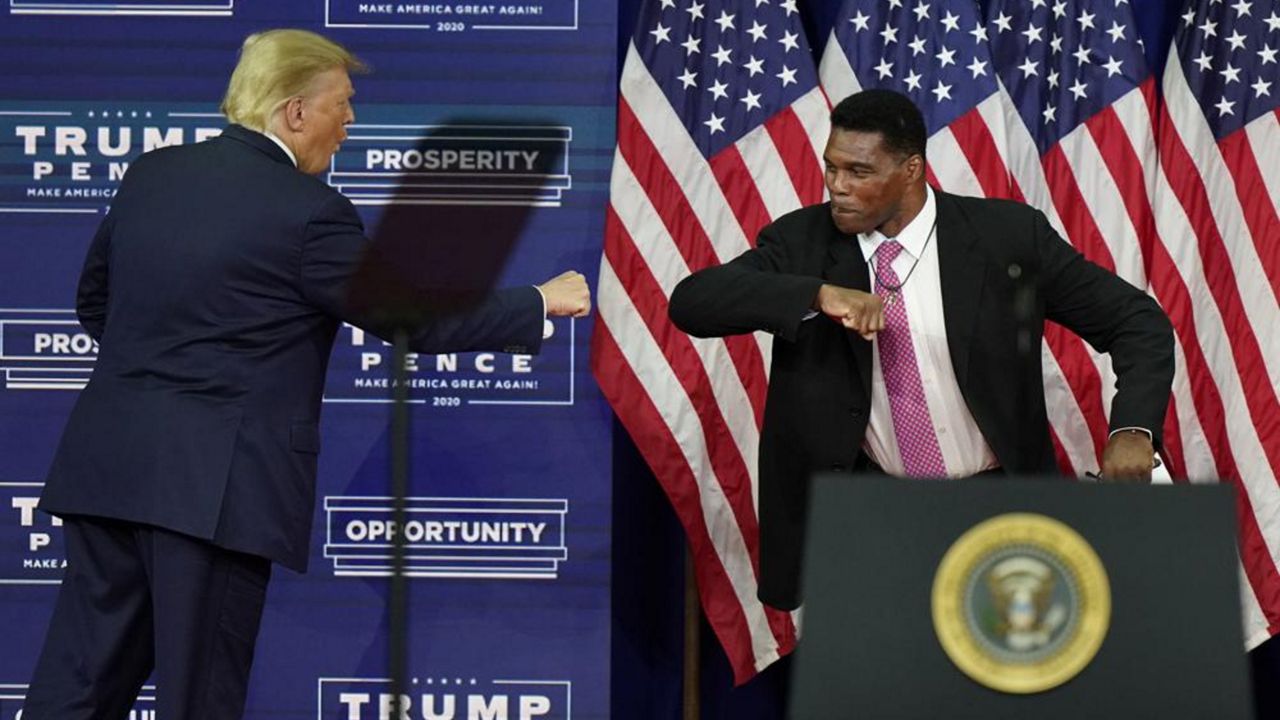 In this Sept. 25, 2020 file photo, President Donald Trump bumps elbows with Herschel Walker during a campaign rally in Atlanta. (AP Photo/John Bazemore)